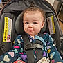 Amber is registered to the contest to win money with this photo: baby, car_seat, child, infant, safety_harness, heart_pattern, clothing, curly_hair, topknot, indoors, warning_label, seat_belt, cute, smile, person, portrait, young_child, face, straps, secure