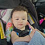 baby, car_seat, child, blanket, seatbelt, car_interior, window, curly_hair, face, infant, safety, striped_blanket, pink, blue, floral_pattern, seat, cute, indoor, portrait, young_child