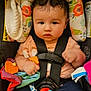 Amber is registered to the contest to win money with this photo: baby, car_seat, child, toy, curly_hair, colorful, infant, clothing, seatbelt, headrest, cute, indoor, sitting, expression, face, hand, footwear, fabric, pattern, person