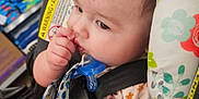 Amber is registered to the contest to win money with this photo: attention, baby, car_seat, child, closeup, clothing, curly_hair, cushion, cute, face, floral_pattern, hand, indoor, infant, pacifier, portrait, seatbelt, secure, sitting, warning_label