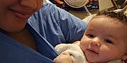 Amber is registered to the contest to win money with this photo: adult, baby, blanket, casual, child, clothing, cozy, curly_hair, cute, face, fan, holding, home, indoor, infant, person, portrait, relaxed, smile, tapestry