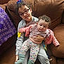 Savannah is registered to the contest to win money with this photo: child, baby, glasses, couch, sweatshirt, hair_clip, pink_jacket, floral_leggings, socks, holding, indoor, portrait, curly_hair, young, seated, cozy, family, cute, smiling, toy