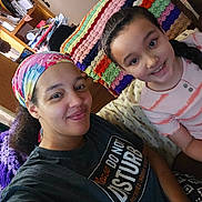 Savannah joined the competition — help win amazing prizes! adult, braids, casual_clothing, child, colorful, cozy, crocheted_blanket, face, furniture, happy, headscarf, home, indoor, living_room, person, portrait, seated, selfie, smile, tshirt