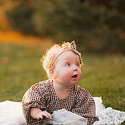 Hallie joined the competition — help win amazing prizes! baby, child, grass, outdoor, curly_hair, headband, dress, blonde, portrait, cute, infant, nature, sunlight, greenery, candid, expression, young, smiling, playing, daylight