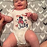 baby, infant, smiling, onesie, clothing, hand, blanket, pattern, celebration, 4th_of_july, laying_down, person, human, cute, chubby_legs, skin, indoors, holding_hand, happy, young_child