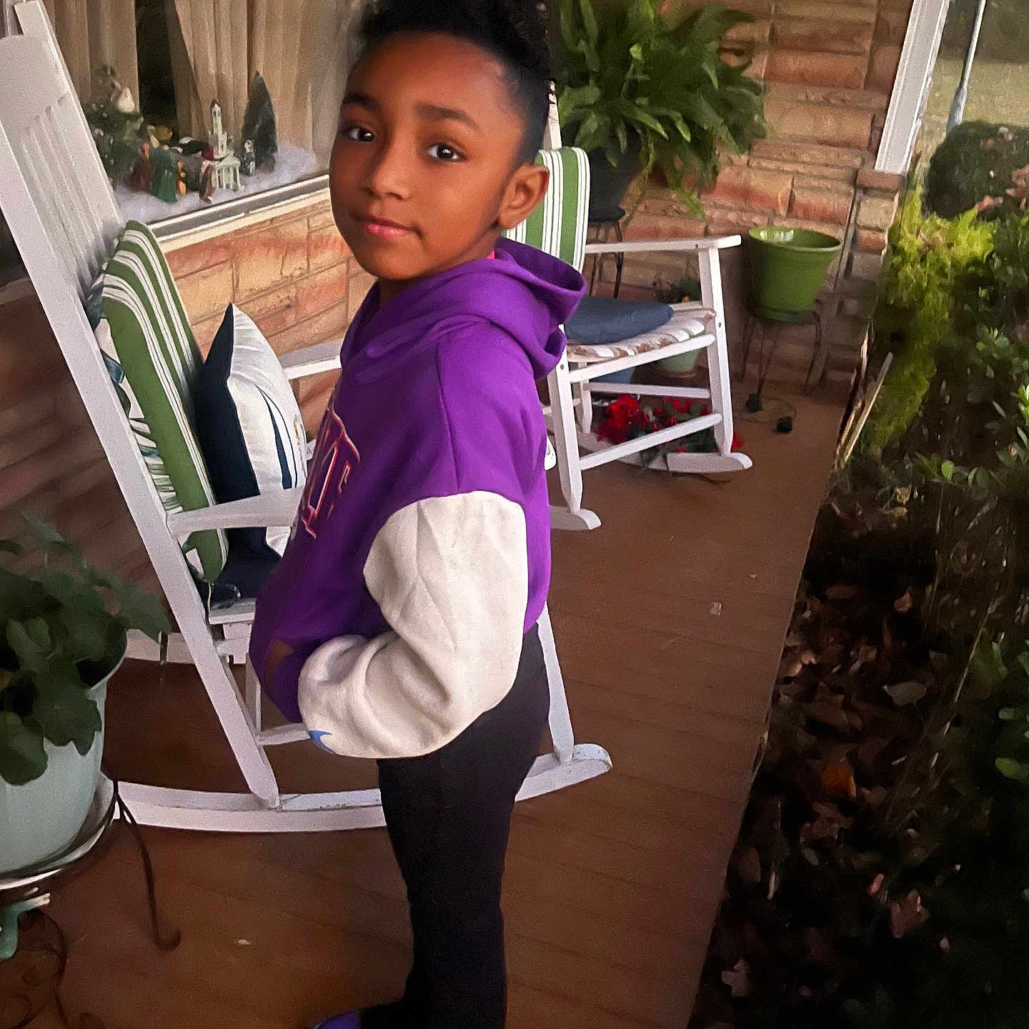 Kyleigh joined the competition — help win amazing prizes! black_pants, brick_wall, calm, casual_clothing, child, evening_light, greenery, home, hoodie, outdoor, person, plant, porch, potted_plant, purple, rocking_chair, shoes, sneakers, standing, wooden_floor