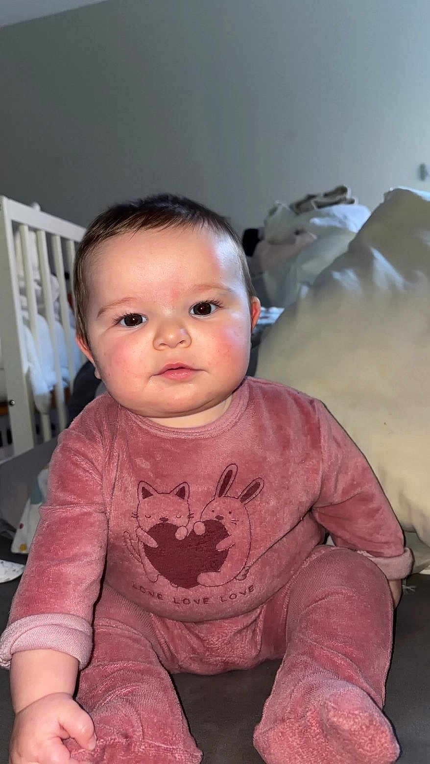 Alya a rejoint le concours — aidez-le/la à gagner de superbes lots ! baby, infant, child, pink_outfit, cute, face, eyes, sitting, indoor, cozy, plush_clothing, couch, pillow, crib, furniture, hand, expression, portrait, young_child, soft_lighting