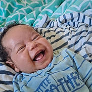 Ny'Gel is registered to the contest to win money with this photo: baby, bed, blanket, blue_onesie, child, cozy, cute, face, happy, indoor, infant, laughing, natural_light, person, portrait, smiling, soft, striped_clothing, window, young