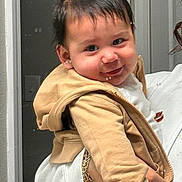 Angel is registered to the contest to win money with this photo: toddler, child, smile, hoodie, beige_clothing, person, indoor, portrait, cute, baby, hand, adult, holding, fashion, face, hair, sleeve, jacket, white_clothing, expression