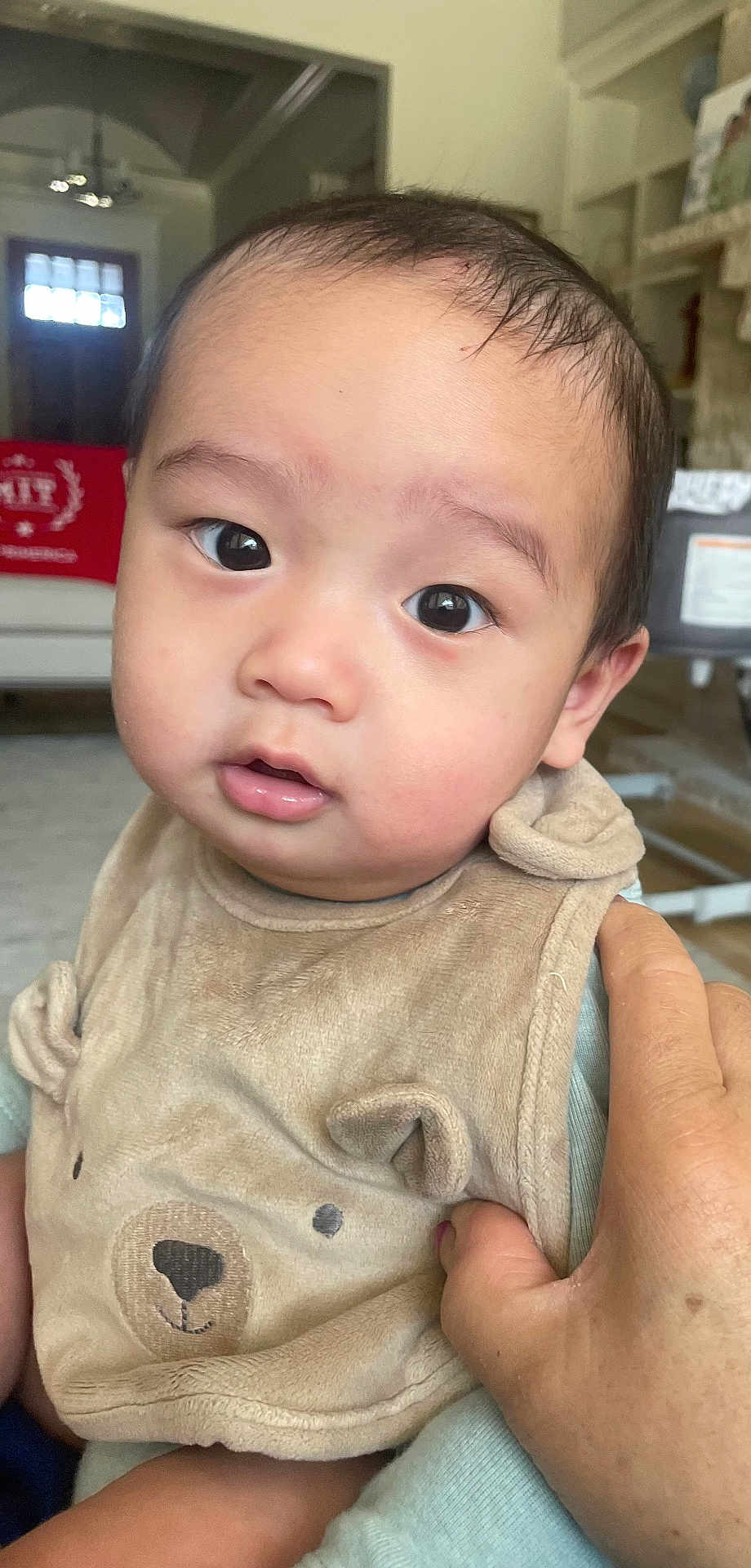 Mung is registered to the contest to win money with this photo: baby, child, face, eyes, hand, bib, clothing, indoor, person, portrait, cute, infant, skin, expression, holding, young, human, apparel, closeup, soft_lighting