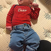 Xavier joined the competition — help win amazing prizes! baby, infant, child, person, clothing, shirt, denim, jeans, socks, striped_shirt, yawning, mattress, fabric, cute, sleepy, raised_fist, casual_wear, indoor, portrait, relaxed