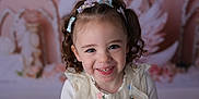 Elia a rejoint le concours — aidez-le/la à gagner de superbes lots ! background, celebration, child, childhood, curly_hair, cute, dress, face, fashion, floral_embroidery, girl, hair_bows, happy, indoor, pastel_colors, pigtails, portrait, smile, studio, young