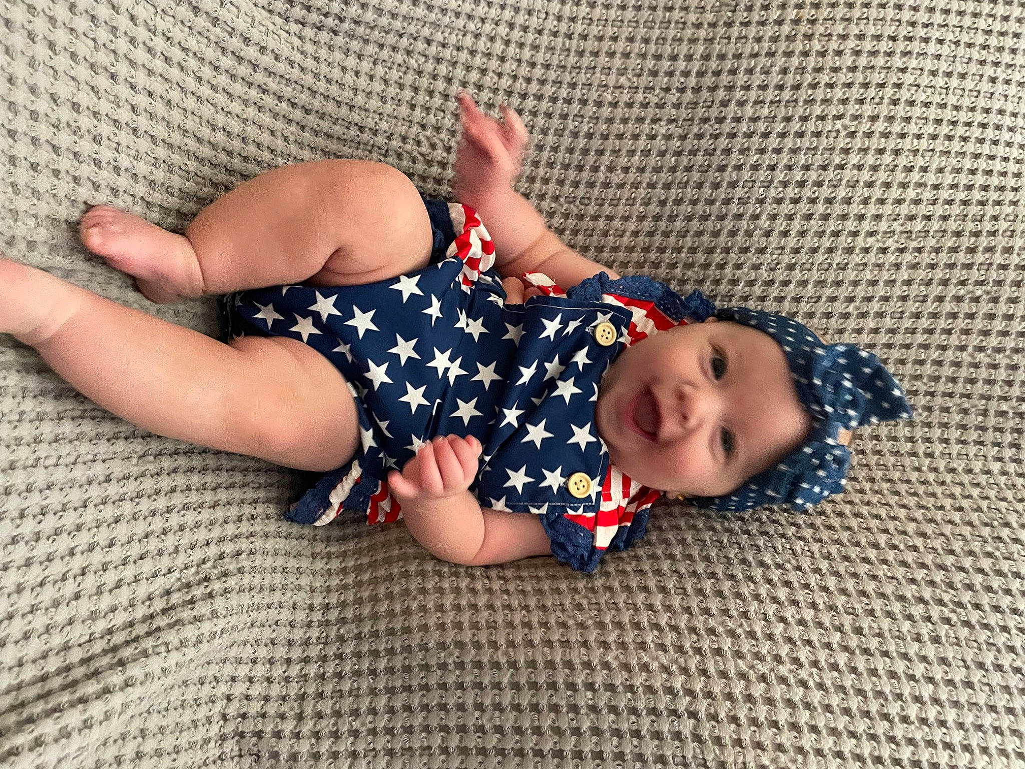 Emersyn is registered to the contest to win money with this photo: baby, baby_toddler_clothing, child, comfort, electric_blue, flooring, foot, hand, headgear, headwear, human_leg, knee, leg, linens, nail, pattern, person, sleeve, sock, thigh