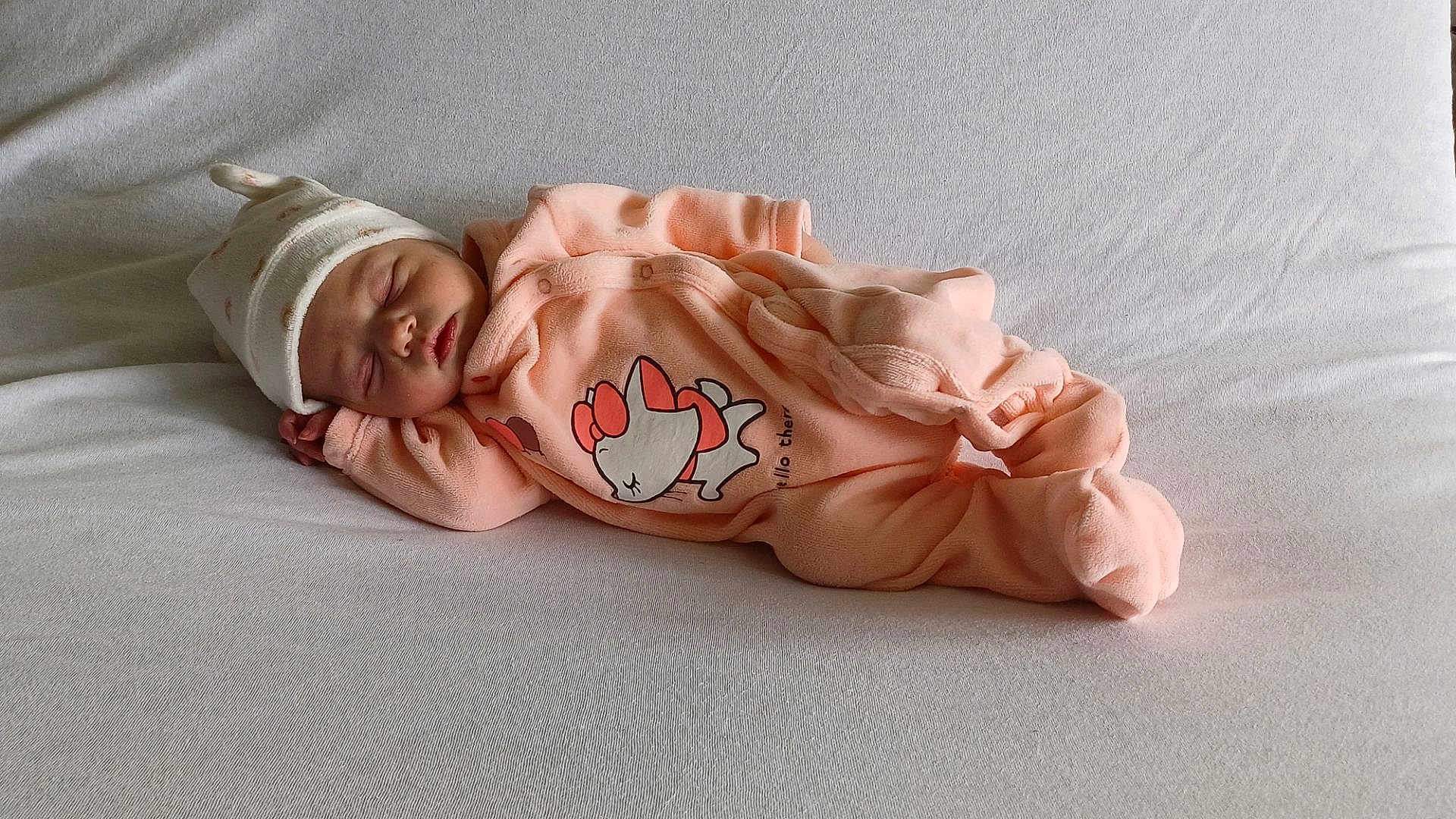 Margot participe au concours pour gagner de l'argent avec cette photo : baby, sleeping, newborn, onesie, hat, blanket, soft, infant, peaceful, cute, resting, cozy, child, portrait, indoor, fabric, clothing, headwear, relaxed, lying_down
