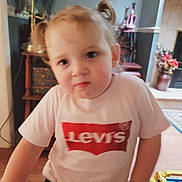 Sarah is registered to the contest to win money with this photo: toddler, child, indoor, pigtails, tshirt, levi's, toy, floor, furniture, home, decor, person, young_child, face, hair, wood_floor, casual, seated, expression, blurred