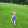child, toddler, girl, barefoot, blue_clothing, floral_pattern, grass, outdoor, nature, trees, jeep, vehicle, greenery, summer, walking, curly_hair, ribbons, daylight, park, casual