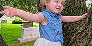 Sarah is registered to the contest to win money with this photo: arms_outstretched, casual_clothing, child, daylight, denim, dress, forest, grass, greenery, happy, nature, outdoor, park, person, playful, smiling, toddler, tree, trunk, young_child