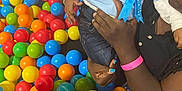 Dayzie joined the competition — help win amazing prizes! child, toddler, adult, hand, ball_pit, colorful_balls, blue_ribbon, clothing, jeans, nail_polish, play_area, indoor, person, skin, face, holding, pink_wristband, black_shirt, toy, fun