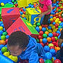 child, ball_pit, colorful_balls, foam_blocks, playground, indoor_play_area, kids_playing, blue_hoodie, pink_shirt, numbers, letters, bright_colors, fun, active, play, young_children, toys, recreation, happy, leisure