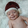 baby, smiling, hat, knitted_hat, red_hat, white_fluffy_background, infant, cute, happy, skin, lying_down, portrait, child, headwear, newborn, holiday, cozy, soft_texture, face, young_child