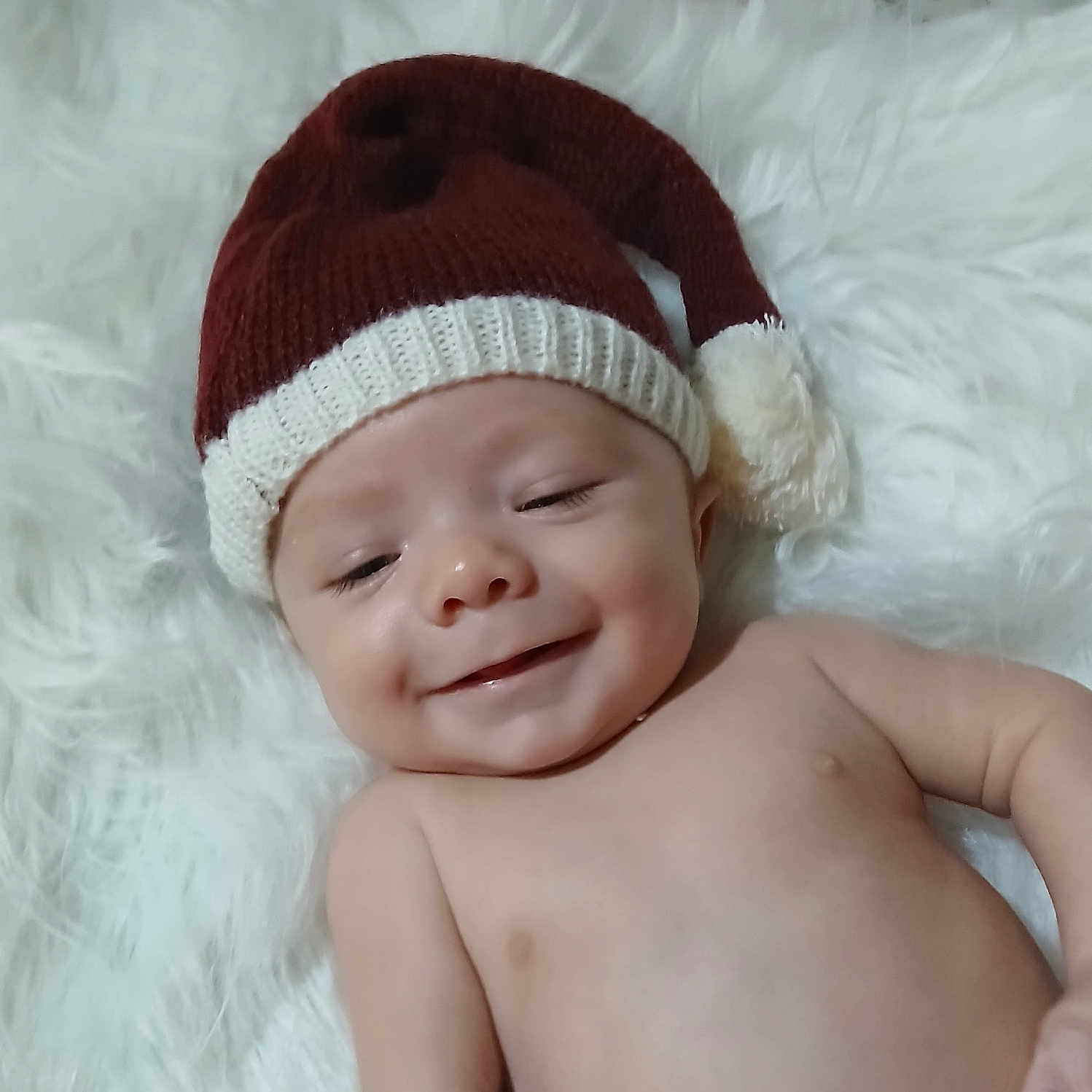 Braxton is registered to the contest to win money with this photo: baby, child, cozy, cute, face, happy, hat, headwear, holiday, infant, knitted_hat, lying_down, newborn, portrait, red_hat, skin, smiling, soft_texture, white_fluffy_background, young_child