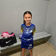 Lina participe au concours pour gagner de l'argent avec cette photo : child, girl, sports_uniform, locker_room, bench, sports_bag, handball, smile, pink_shoes, tiled_floor, indoor, portrait, standing, shorts, socks, young, confident, hair_tied_back, team_sport, athlete