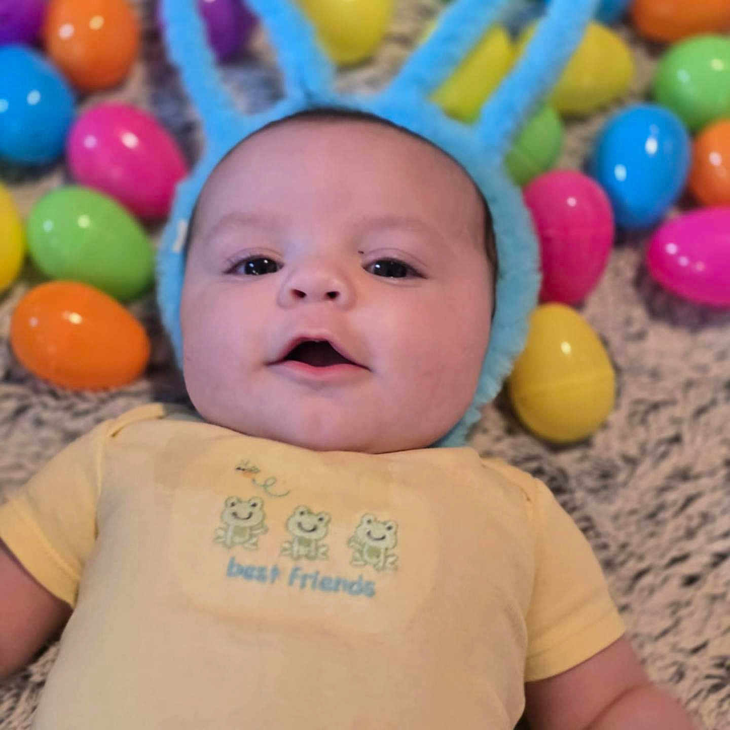 Logan is registered to the contest to win money with this photo: accessories, baby, balloon, cap, clothing, face, happy, hat, head, newborn, people, person, photography, portrait, purple, quilt, skin, smile, t_shirt, tattoo