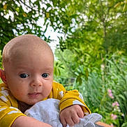 Xander is registered to the contest to win money with this photo: baby, blanket, child, closeup, cute, expression, face, flora, garden, greenery, hands, infant, nature, outdoor, peaceful, portrait, skin, soft_light, yellow_clothing, young