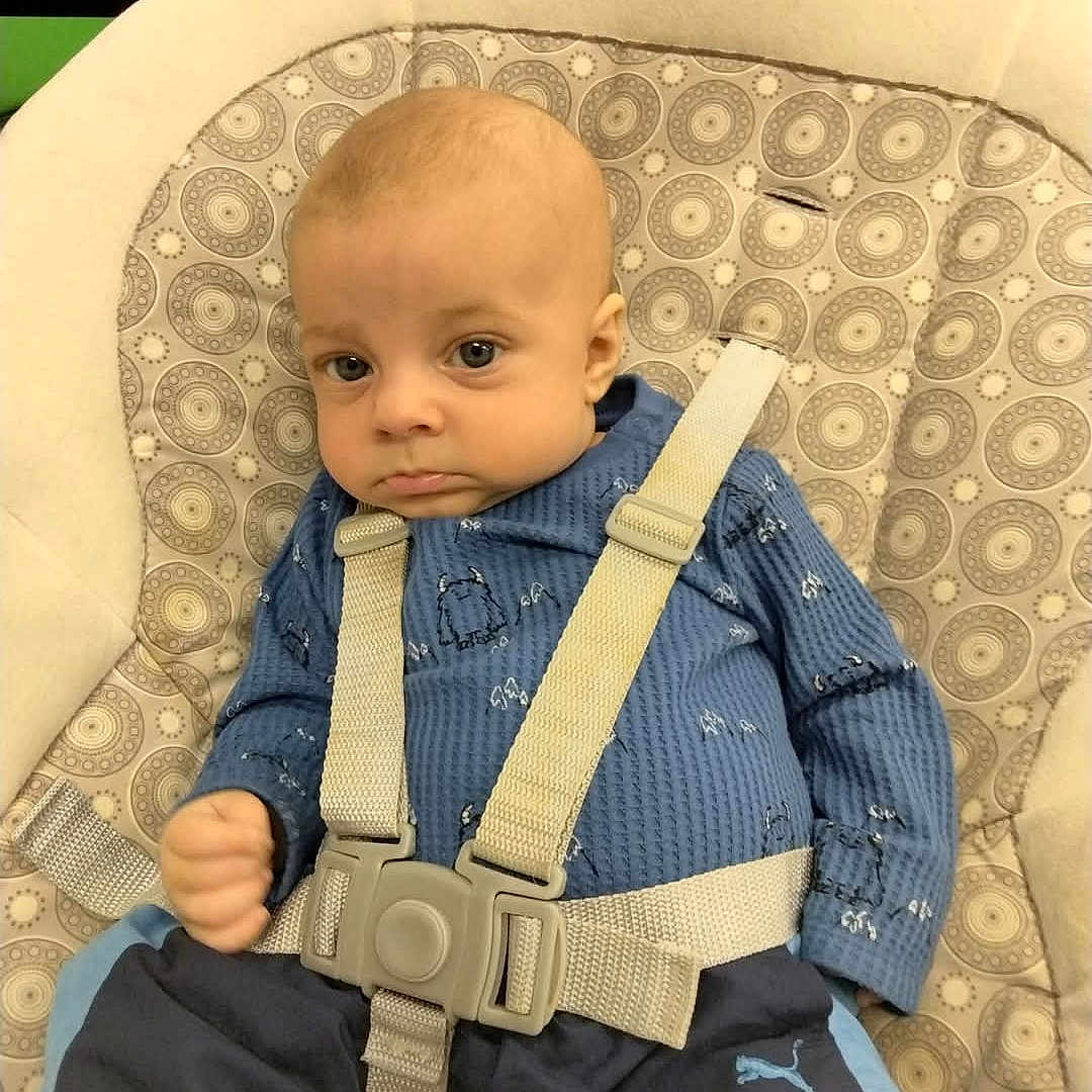 Mason joined the competition — help win amazing prizes! baby, baby_seat, blue_clothing, child, cushion, cute, face, furniture, hands, head, indoor, infant, patterned_fabric, person, puma_logo, seatbelt, serious_expression, sitting, small_person, straps