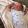 arms_stretched, baby, blanket, child, cozy, cute, floral_pattern, head, indoors, infant, newborn, onesie, peaceful, person, portrait, resting, skin, sleep, sleeping, soft_texture