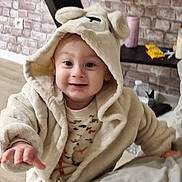 Kais a rejoint le concours — aidez-le/la à gagner de superbes lots ! toddler, child, smiling, robe, hood, indoor, brick_wall, baby, cute, hand, face, clothing, pacifier, table, water_bottle, furniture, person, happy, young_child, cozy