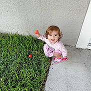 Paula is registered to the contest to win money with this photo: toddler, child, grass, toy, ball, pink_clothing, curly_hair, outdoor, concrete, play, squatting, smiling, minnie_mouse, footwear, happy, person, young_child, daylight, greenery, cute