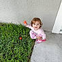 toddler, child, grass, toy, ball, pink_clothing, curly_hair, outdoor, concrete, play, squatting, smiling, minnie_mouse, footwear, happy, person, young_child, daylight, greenery, cute