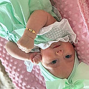 Valencia-Marie is registered to the contest to win money with this photo: baby, infant, child, mint_green, bow, bracelet, blanket, pink, soft_texture, clothing, headwear, face, portrait, lying_down, cute, skin, hand, eyes, expression, indoor