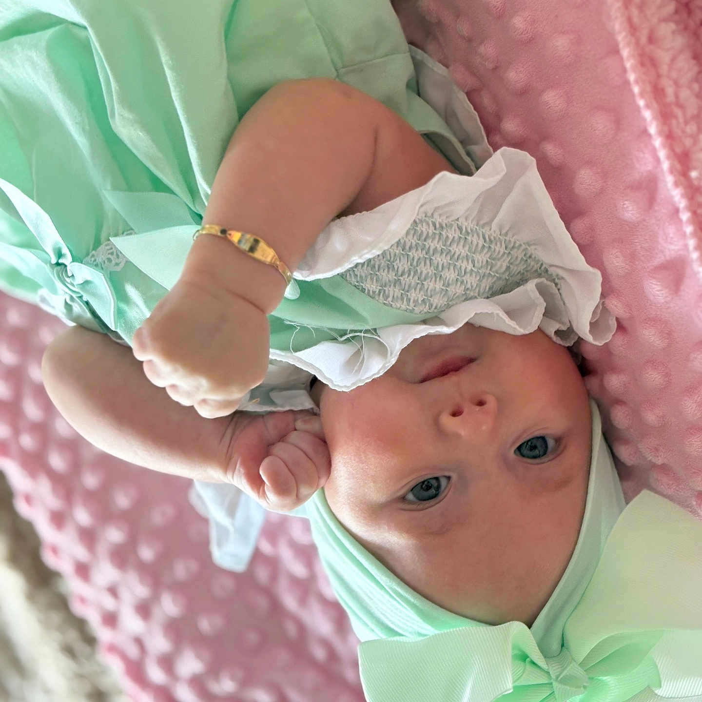 Valencia-Marie is registered to the contest to win money with this photo: baby, blanket, bow, bracelet, child, clothing, cute, expression, eyes, face, hand, headwear, indoor, infant, lying_down, mint_green, pink, portrait, skin, soft_texture