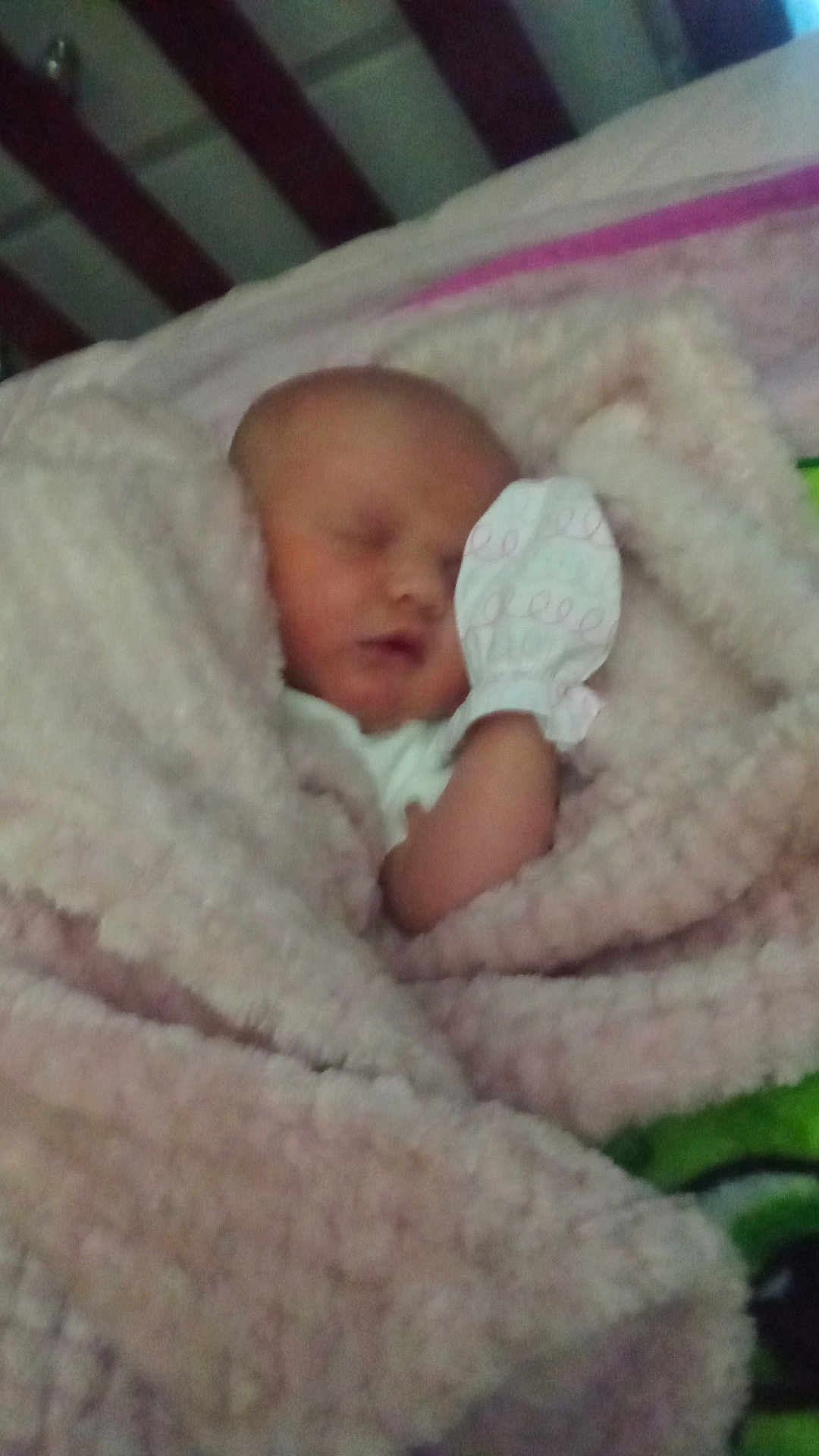 Michelle is registered to the contest to win money with this photo: baby, newborn, sleeping, blanket, mitten, crib, wood, soft, cozy, infant, child, bed, rest, peaceful, closeup, wrapped, face, indoors, person, comfort