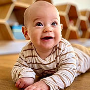 Soan a rejoint le concours — aidez-le/la à gagner de superbes lots ! baby, child, smiling, striped_shirt, floor, wooden_floor, indoor, face, happy, cute, portrait, hands, head, eyes, furniture, shelf, honeycomb_shelf, person, toddler, clothing