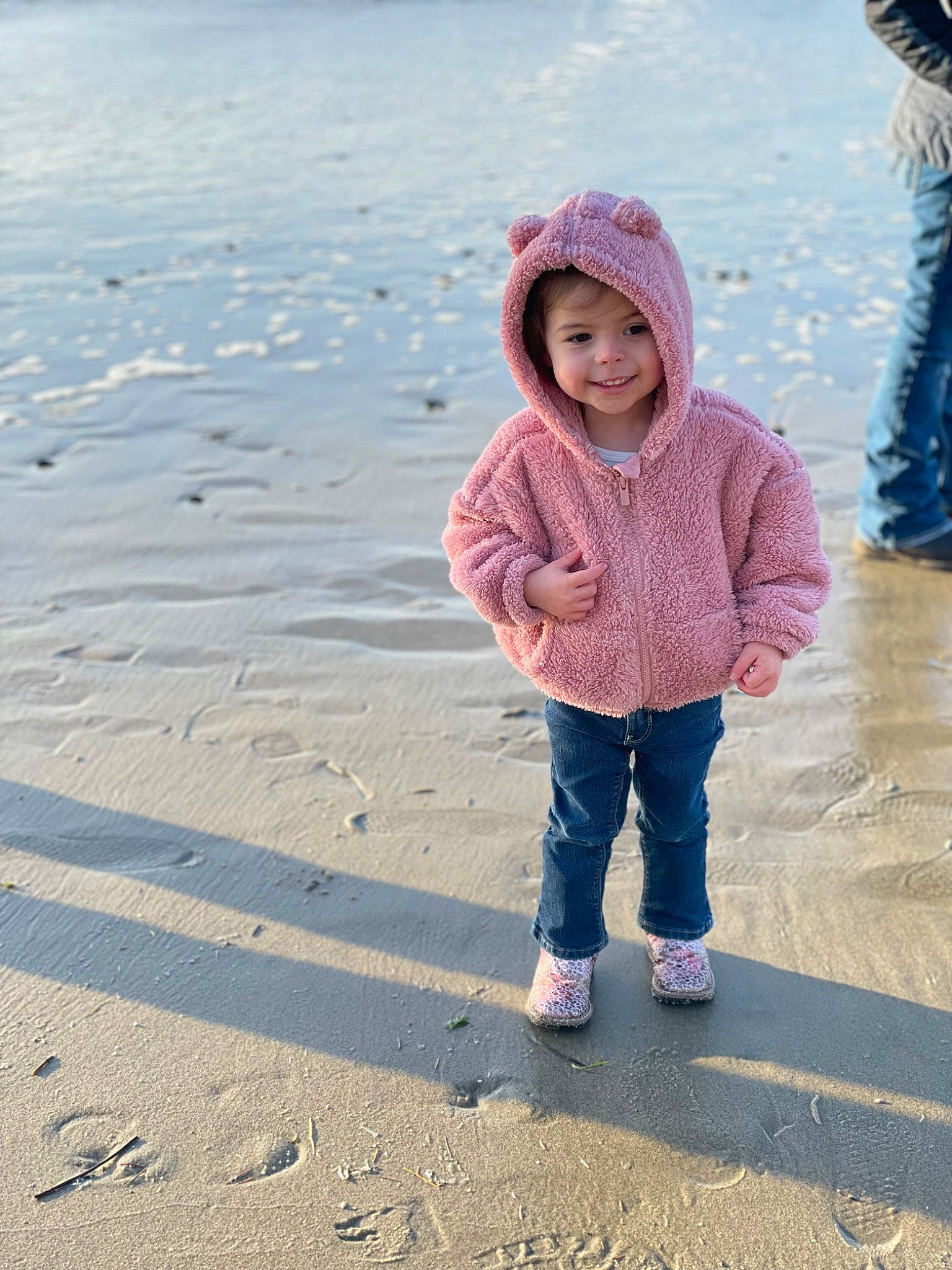 Adalyn joined the competition — help win amazing prizes! baby_toddler_clothing, beach, cap, child, freezing, fun, happy, hat, headwear, jacket, jeans, joy, landscape, people_in_nature, person, reflection, sand, sleeve, smile, standing