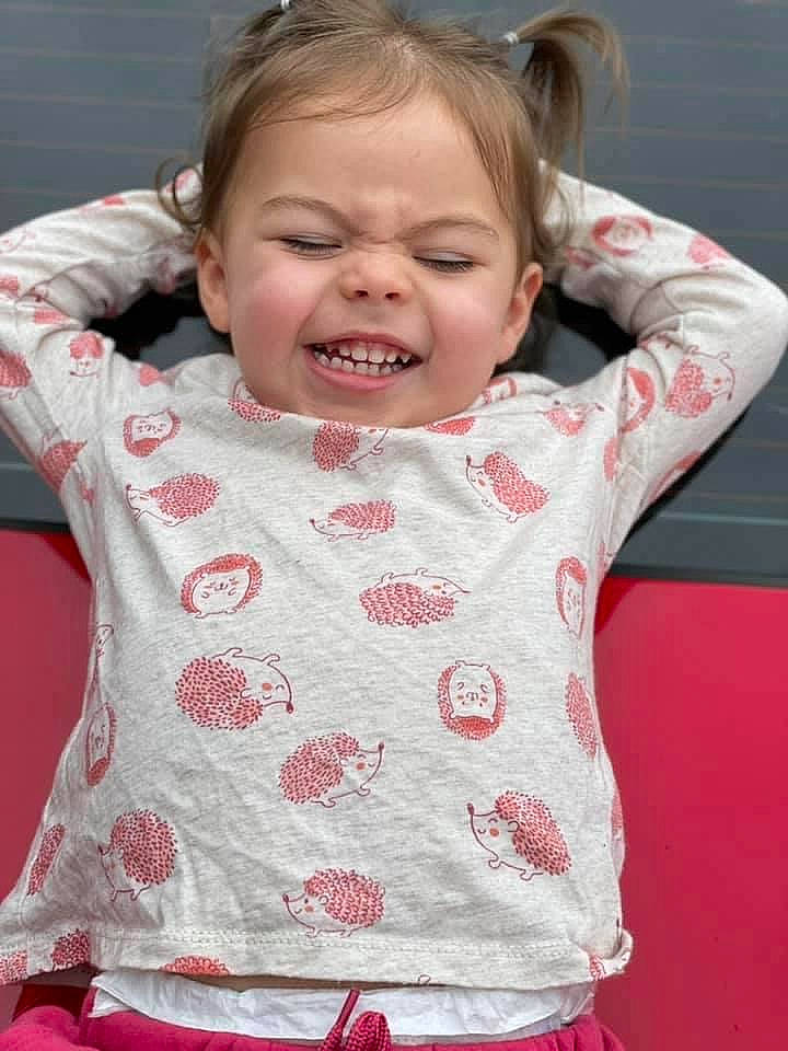 Adalyn is registered to the contest to win money with this photo: arm, baby_toddler_clothing, cheek, chin, face, finger, gesture, happy, head, lip, mouth, neck, nose, organ, person, pink, shoulder, skin, sleeve, smile