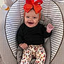 baby, infant, smiling, orange_bow, baby_rocker, striped_cushion, floral_pants, white_socks, hanging_toys, indoor, happy, cute, child, headwear, clothing, seat, playful, portrait, person, carpet