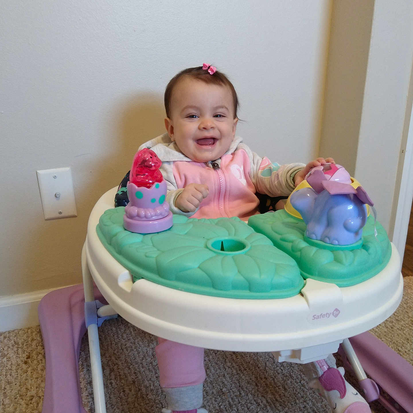 Insaf is registered to the contest to win money with this photo: baby, carpet, child, clothing, cute, face, footwear, girl, happy, home, indoor, infant, person, pink, play, sitting, smile, toy, walker, young