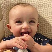 Peter Curtis is registered to the contest to win money with this photo: baby, smiling, happy, face, hands, plush_toy, child, indoor, closeup, cute, joyful, infant, patterned_background, person, blue_clothing, skin, expression, young_child, playful, toddler