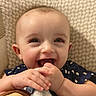 baby, smiling, happy, face, hands, plush_toy, child, indoor, closeup, cute, joyful, infant, patterned_background, person, blue_clothing, skin, expression, young_child, playful, toddler