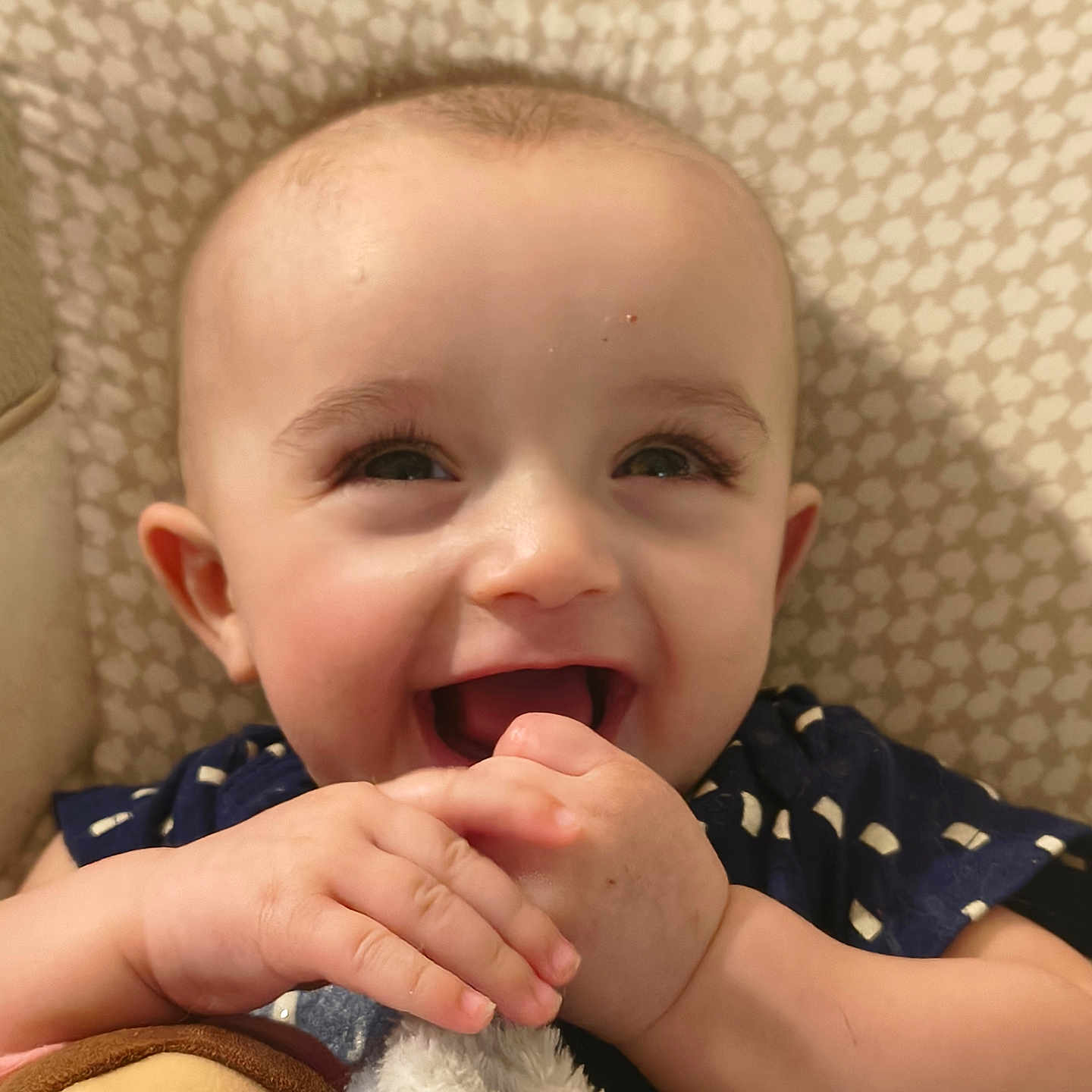Peter Curtis is registered to the contest to win money with this photo: baby, smiling, happy, face, hands, plush_toy, child, indoor, closeup, cute, joyful, infant, patterned_background, person, blue_clothing, skin, expression, young_child, playful, toddler