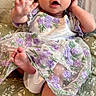 baby, child, infant, dress, headband, purple, flower, pattern, cushion, sitting, hand, foot, cute, portrait, indoor, fabric, cloth, smile, young, person
