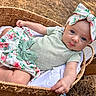 baby, basket, blue_eyes, child, closeup, curious, cute, floral_pattern, green_clothing, hands, headband, infant, lying_down, nature, outdoor, portrait, skirt, soft_light, wood, woven