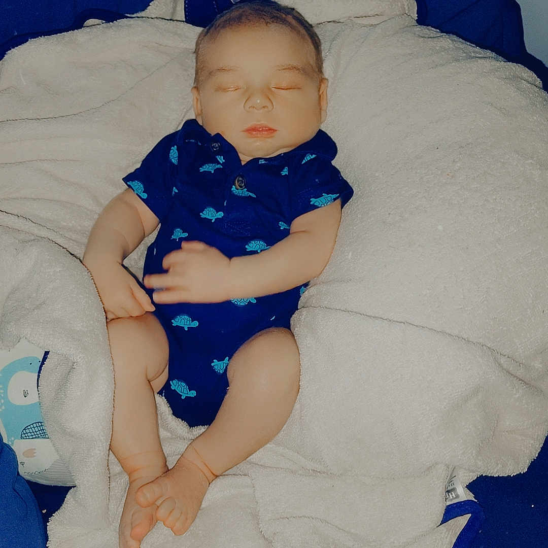 Jasper is registered to the contest to win money with this photo: baby, sleeping, blue_onesie, blanket, owl_pillow, infant, turtle_prints, cozy, cute, soft_texture, bed, child, peaceful, indoors, resting, newborn, comfort, portrait, blue, white