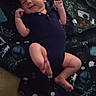 baby, infant, onesie, blanket, carpet, smile, face, skin, limbs, child, newborn, cute, indoors, floor, pattern, clothing, lying_down, happy, small, young