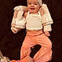 baby, smiling, infant, headband, pink_pants, white_tank_top, fluffy_jacket, hand, dark_background, happy, cute, child, person, clothing, fabric, portrait, indoors, playful, sitting, small_child