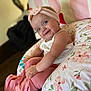 baby, smiling, headband, blue_eyes, pink, white_top, floral_pattern, cushion, indoor, cute, child, sitting, happy, infant, portrait, clothing, pink_pants, soft_lighting, home, playful